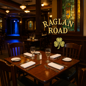 In a warmly decorated paneled room, 3 men and a woman are seated at a wood table with drinks and a basket of chips