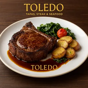 A Smoked Pork Chop on a plate with sauce from Toledo Tapas, Steak & Seafood