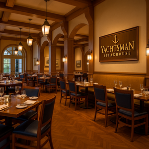 Área de refeições redonda com piso de madeira, teto alto e mesas arrumadas para o jantar