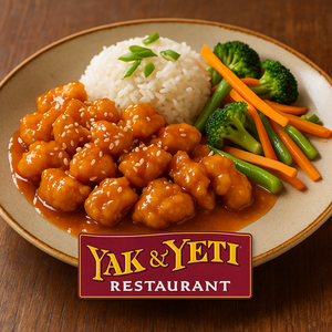 Sala de jantar com decoração do sudeste asiático, dispondo de mesas de madeira e cadeiras esculpidas guardadas por estátuas ferozes